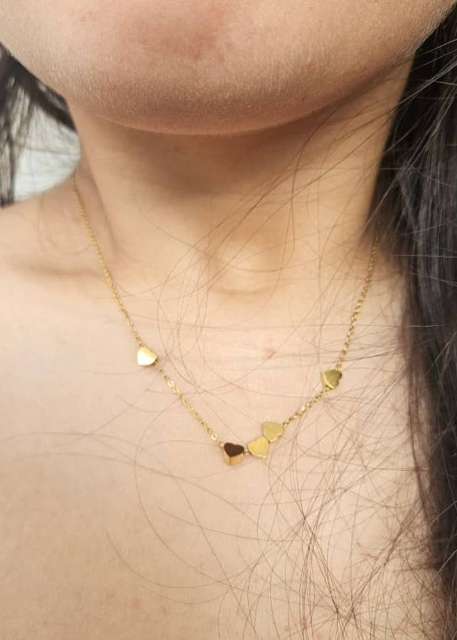 Gold necklace with heart-shaped pendants on a person's neck