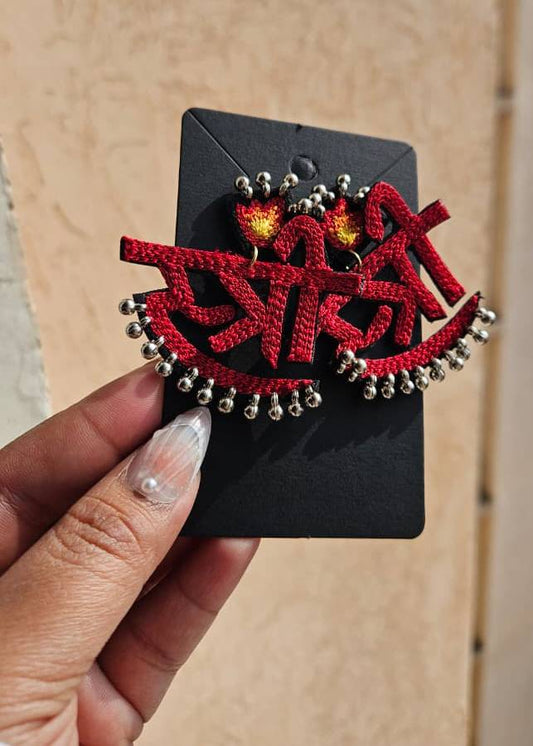 stree Red macrame earrings with silver beads on a black card held by a hand.