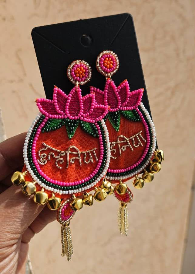 Decorative earrings with pink and gold details on a beige background