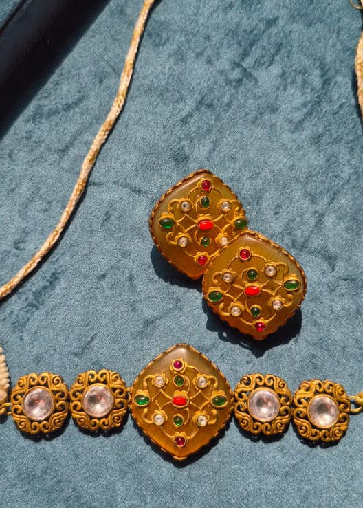 Decorative gold necklace with gemstones on a textured blue surface